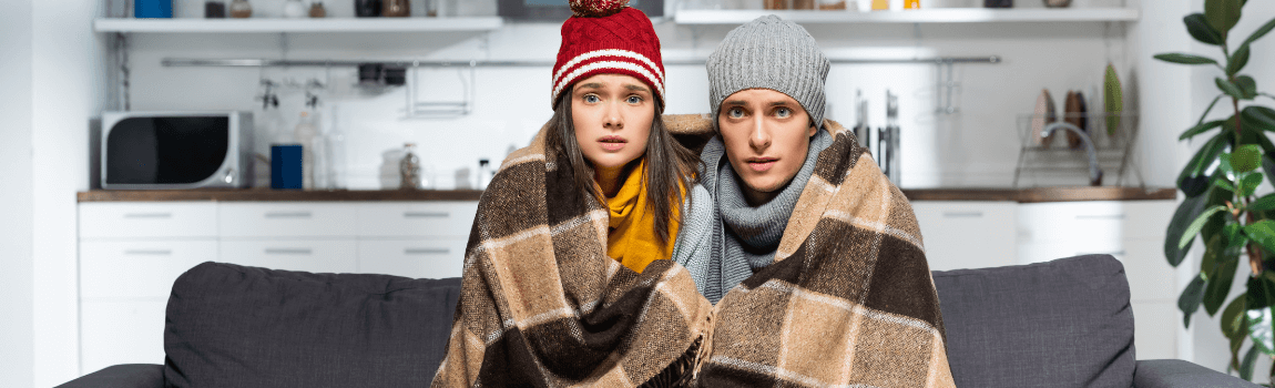 couple sitting on couch with blankets and hats on